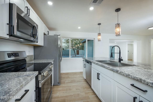 kitchen with light stone counters, sink, white cabinets, and stainless steel appliances