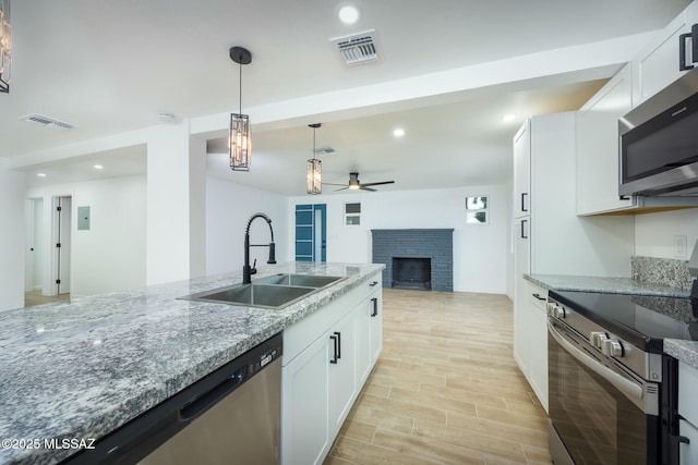 kitchen with white cabinetry, ceiling fan, sink, stainless steel appliances, and light stone counters