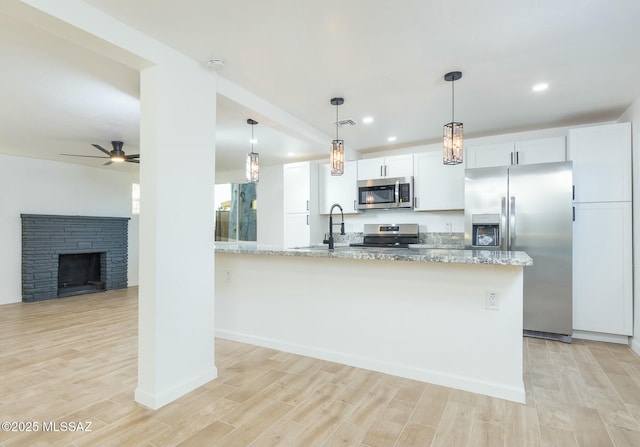 kitchen with stainless steel appliances, white cabinetry, and light stone counters