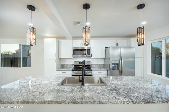 kitchen with white cabinets, light stone counters, hanging light fixtures, and appliances with stainless steel finishes