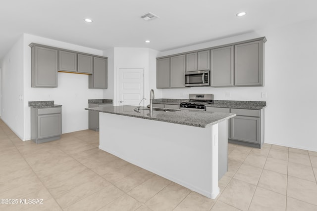 kitchen with gray cabinetry, a center island with sink, stainless steel appliances, and sink