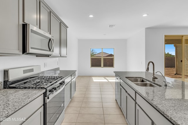 kitchen with light stone countertops, stainless steel appliances, a wealth of natural light, and sink