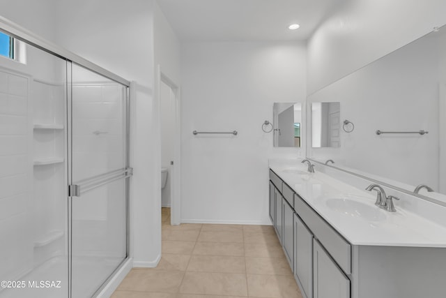 bathroom featuring tile patterned floors, vanity, a shower with shower door, and toilet