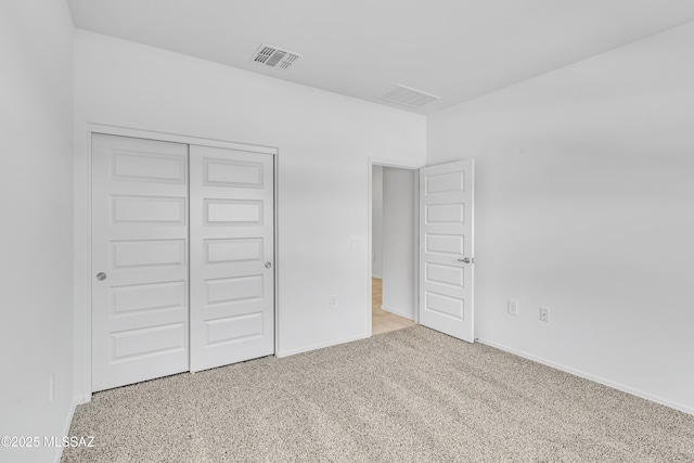 unfurnished bedroom with light colored carpet and a closet