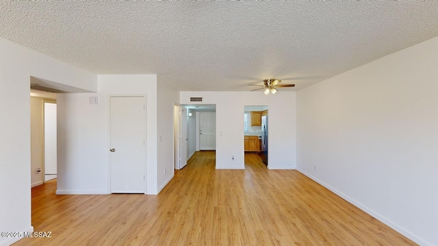 empty room featuring ceiling fan, light hardwood / wood-style floors, and a textured ceiling