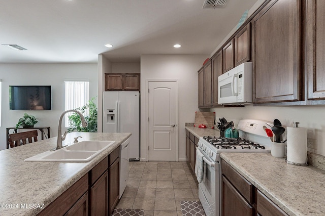 kitchen with dark brown cabinets, sink, and white appliances