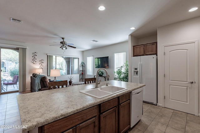 kitchen with light tile patterned flooring, sink, white appliances, an island with sink, and ceiling fan