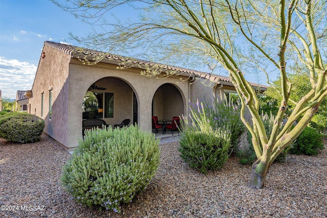 view of side of home with ceiling fan and a patio area