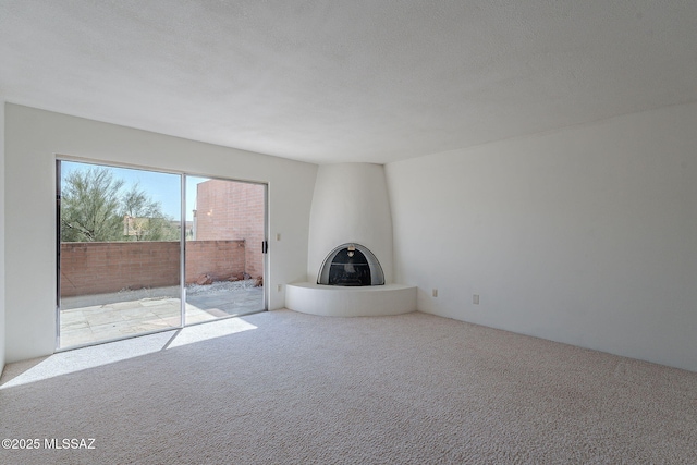 unfurnished living room with carpet floors, a large fireplace, and a textured ceiling