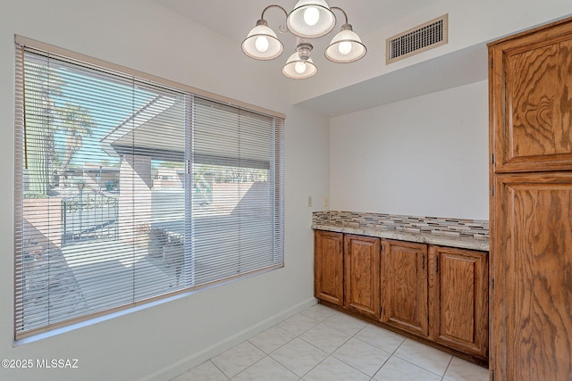 interior space featuring baseboards, visible vents, a chandelier, and light tile patterned flooring