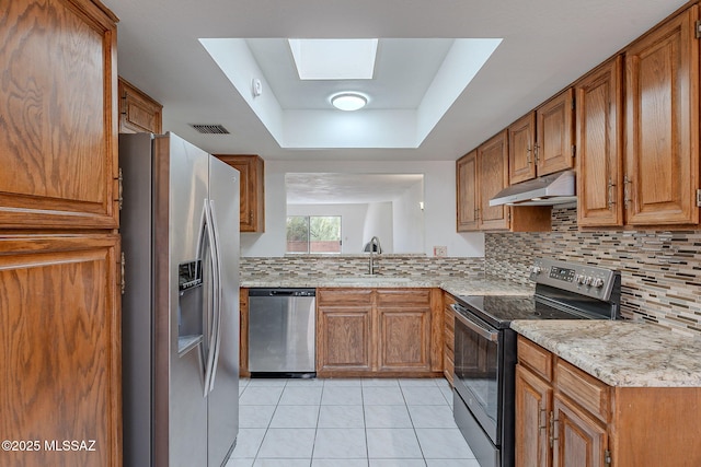 kitchen featuring under cabinet range hood, stainless steel appliances, a skylight, a sink, and visible vents