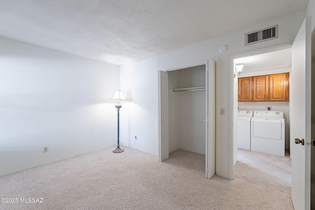 unfurnished bedroom featuring light carpet, washer and clothes dryer, a closet, and visible vents