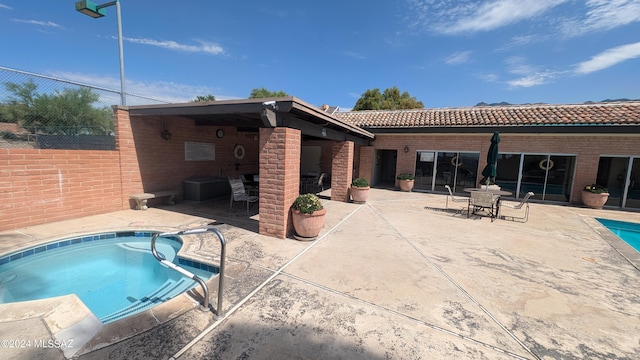 view of swimming pool with a patio area, a jacuzzi, and fence