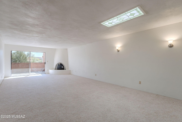 unfurnished living room featuring a textured ceiling, carpet, and a glass covered fireplace