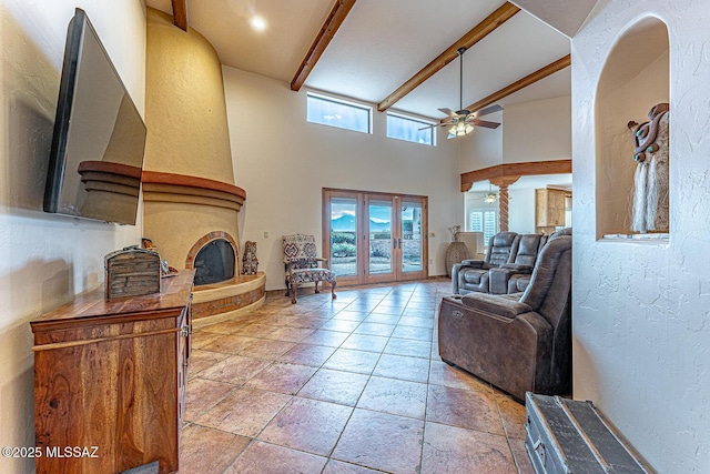 living room with beamed ceiling, french doors, ceiling fan, and a high ceiling