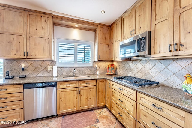 kitchen featuring backsplash, stainless steel appliances, sink, stone counters, and light tile patterned flooring