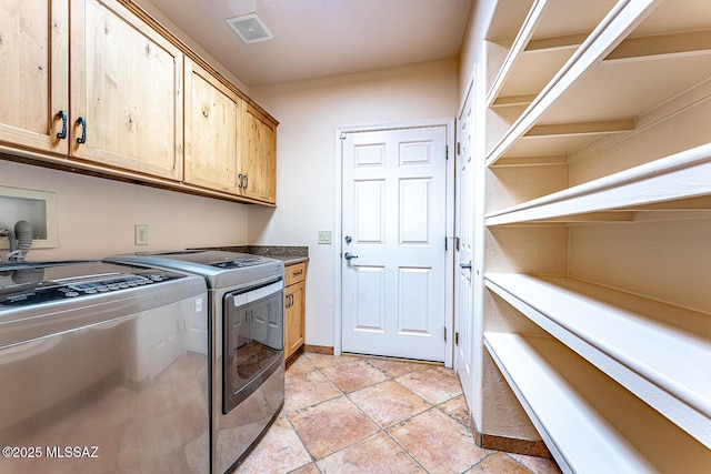 clothes washing area featuring washer and clothes dryer and cabinets