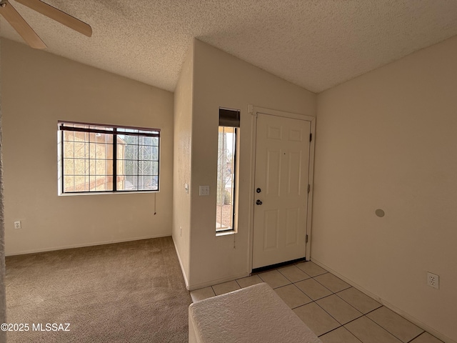 entrance foyer featuring ceiling fan, light tile patterned flooring, lofted ceiling, and a textured ceiling