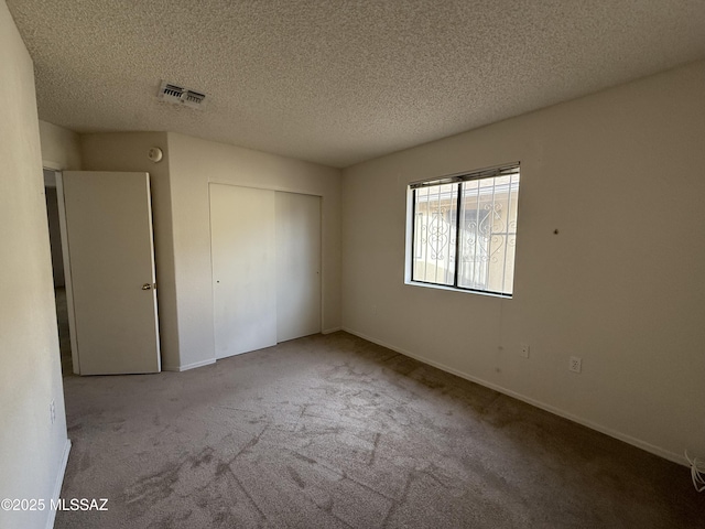 unfurnished bedroom with a textured ceiling, light carpet, and a closet