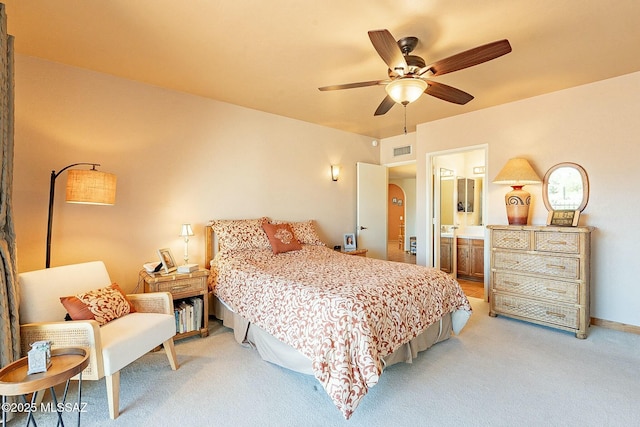 carpeted bedroom with ensuite bath and ceiling fan