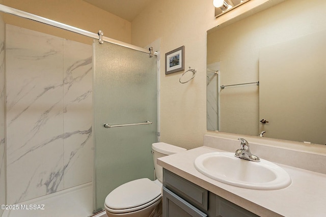 bathroom featuring vanity, a shower with shower door, and toilet