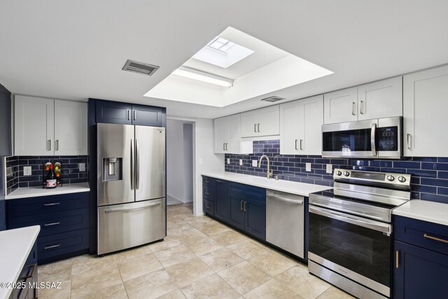 kitchen with blue cabinets, sink, appliances with stainless steel finishes, tasteful backsplash, and white cabinetry