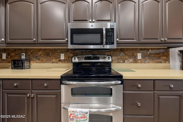 kitchen featuring stainless steel appliances, backsplash, gray cabinets, and light countertops