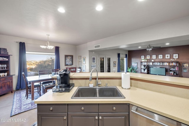 kitchen featuring a sink, gray cabinetry, light countertops, and stainless steel dishwasher