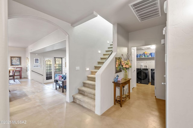 stairway with visible vents, arched walkways, and independent washer and dryer