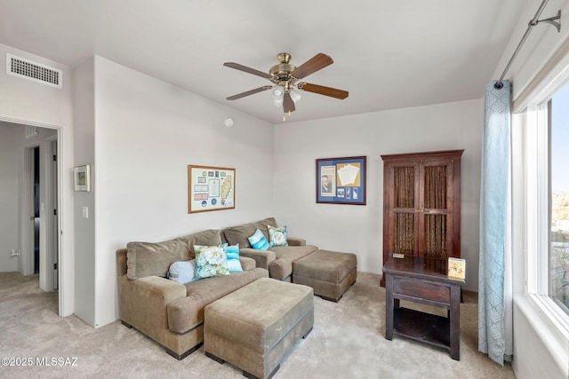 living area with visible vents, light colored carpet, and ceiling fan