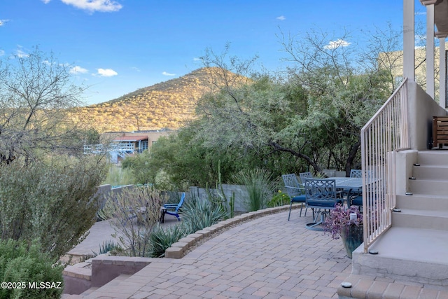 view of patio with outdoor dining area, a mountain view, and stairway