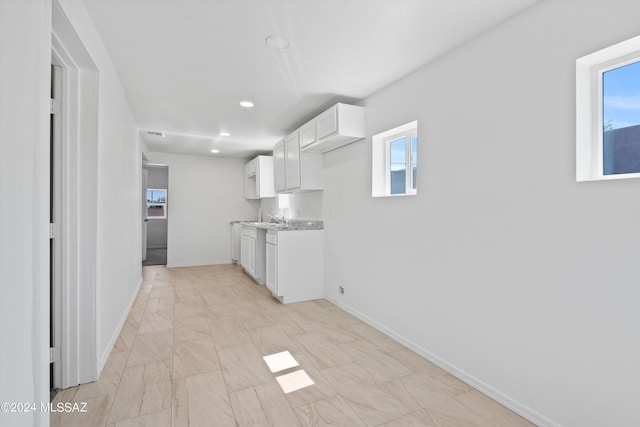 kitchen featuring light stone countertops and white cabinets