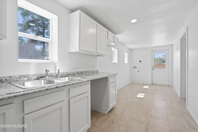 kitchen with light stone counters, sink, and white cabinets