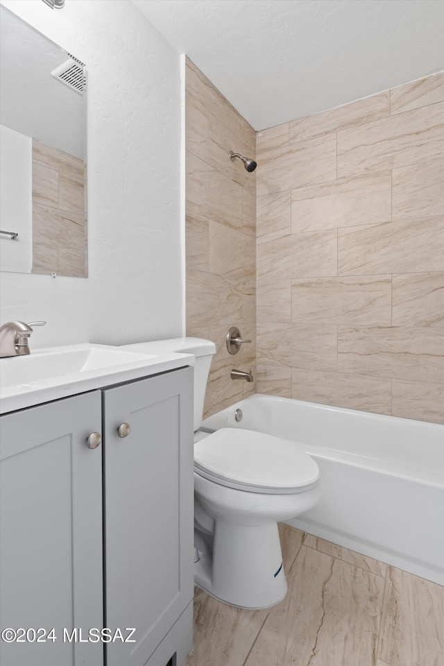 full bathroom featuring tiled shower / bath, vanity, and toilet