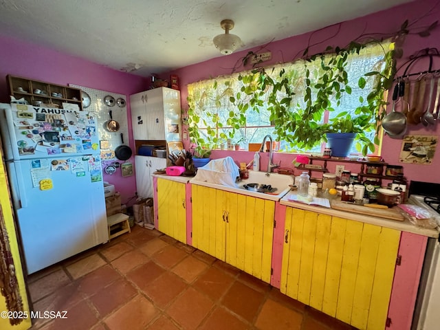 kitchen featuring sink, a textured ceiling, and refrigerator