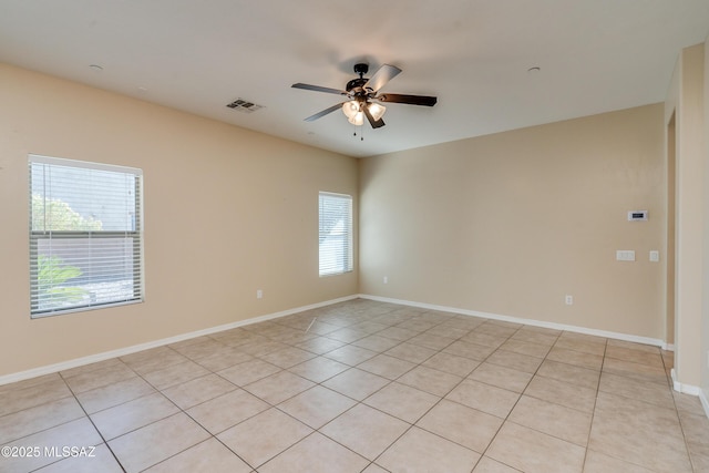 empty room featuring a wealth of natural light, light tile patterned flooring, and ceiling fan