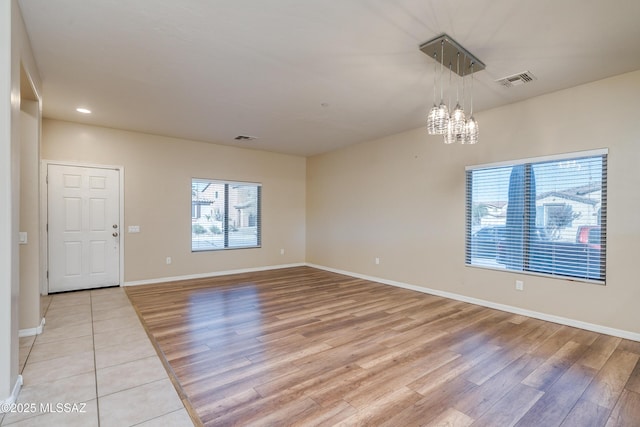 unfurnished room featuring a chandelier and light hardwood / wood-style flooring