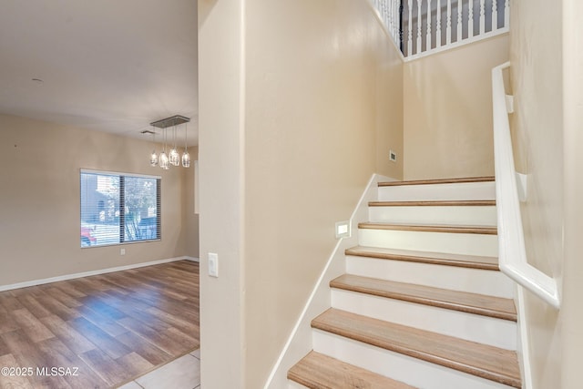 stairway featuring hardwood / wood-style flooring and an inviting chandelier