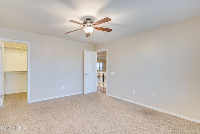 unfurnished bedroom with ceiling fan, light colored carpet, a walk in closet, and a closet