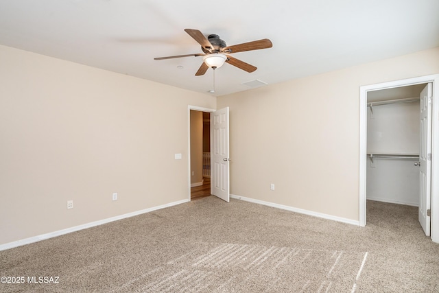 unfurnished bedroom with carpet, a spacious closet, a closet, and ceiling fan