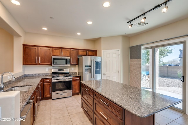 kitchen featuring light stone countertops, sink, a center island, stainless steel appliances, and rail lighting