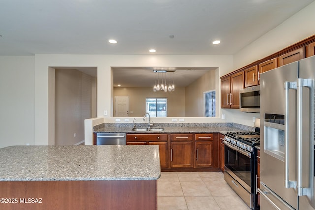 kitchen featuring sink, hanging light fixtures, light stone counters, light tile patterned floors, and appliances with stainless steel finishes