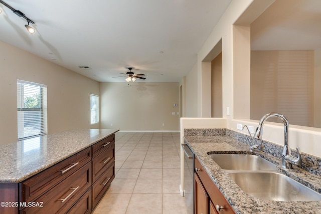 kitchen featuring light stone countertops, sink, dishwasher, and light tile patterned flooring