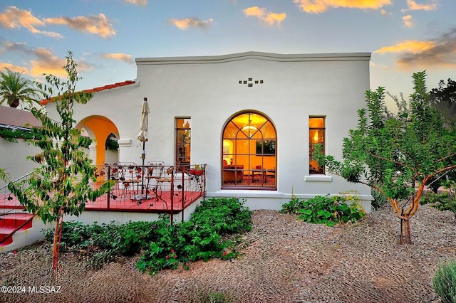 back house at dusk featuring covered porch