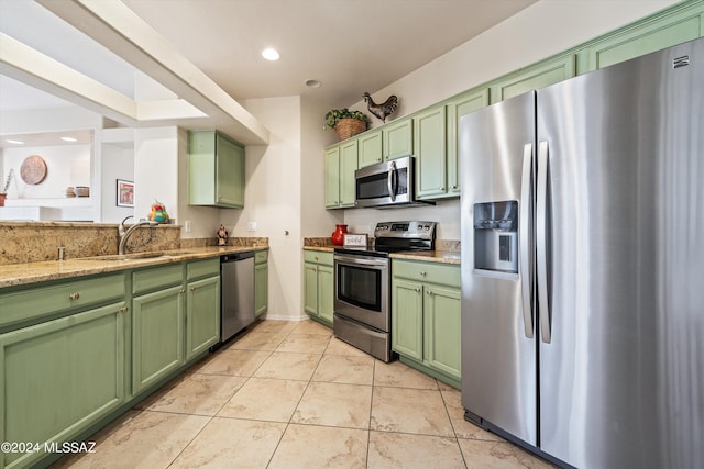 kitchen with sink, stainless steel appliances, light stone counters, light tile patterned floors, and green cabinetry