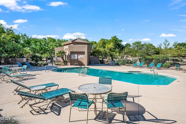 view of pool with a multi sided fireplace and a patio