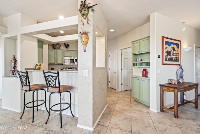 kitchen featuring kitchen peninsula, a kitchen breakfast bar, and green cabinets