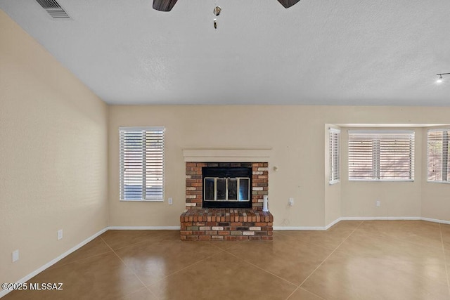 unfurnished living room with ceiling fan, light tile patterned floors, and a brick fireplace