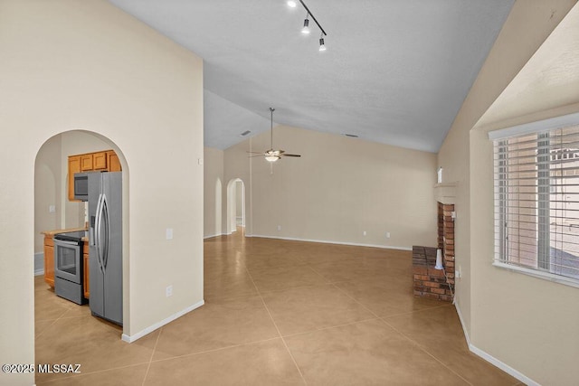 unfurnished living room featuring ceiling fan, light tile patterned flooring, lofted ceiling, and a brick fireplace