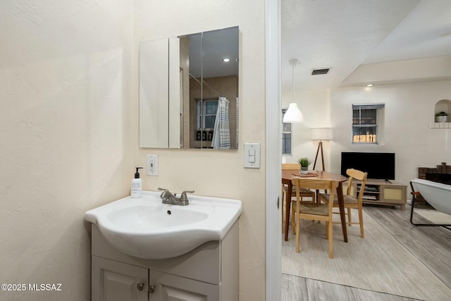 bathroom featuring hardwood / wood-style flooring, vanity, and walk in shower